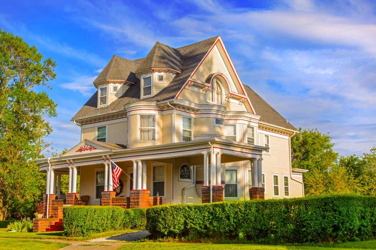 Beautiful Victorian Style home with lush landscaping surrounding the home, blue sky in the background and warm sunset lighting bathing the home in glowing light; Restoring Your Historic Home