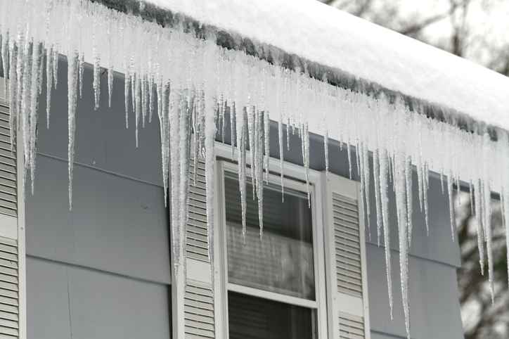 icicles forming an ice dam on a house's roof in winter season