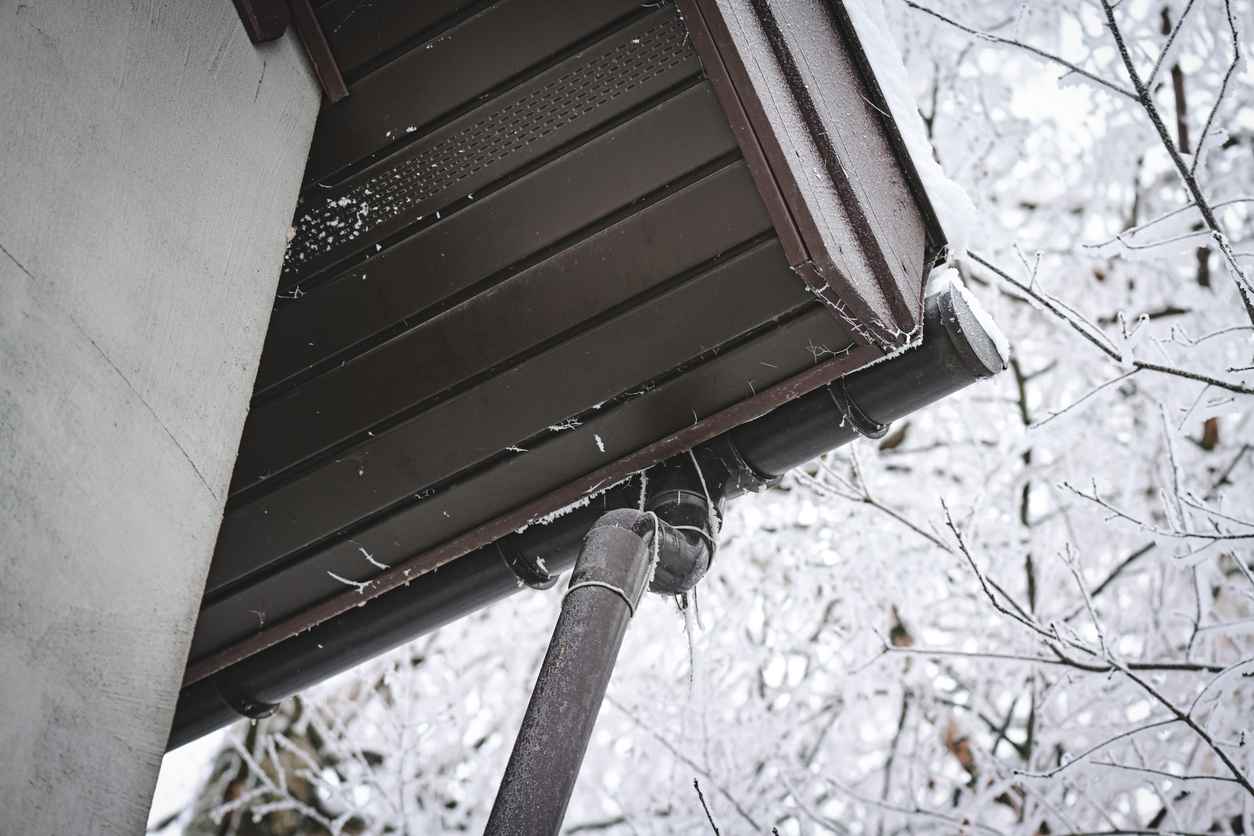 An upward view of a roof and gutter system on a house during winter